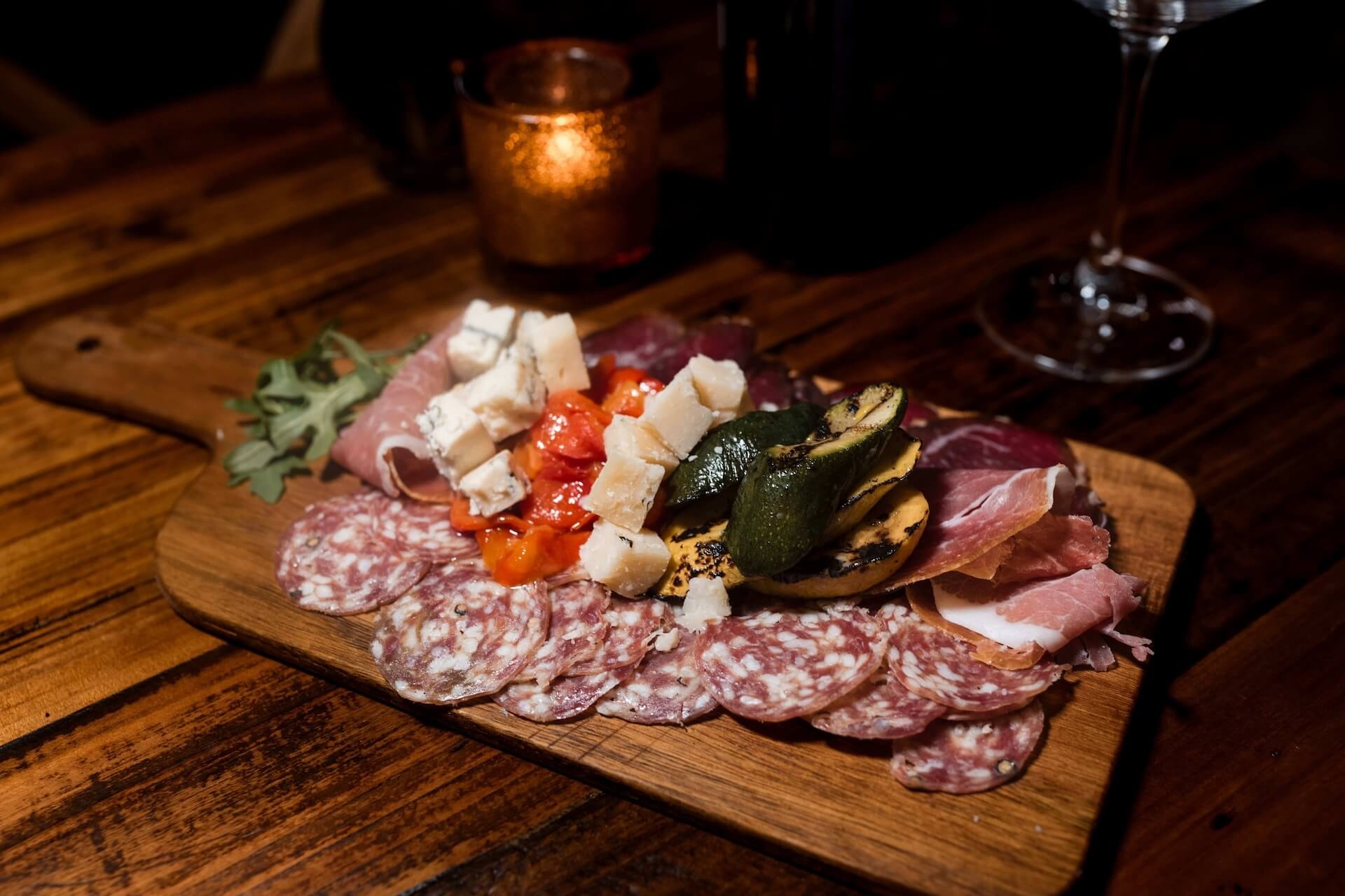 A wooden board of salami, prosciutto, cheese and roasted vegetables